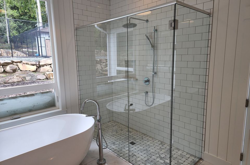 Frameless glass corner shower beside a freestanding tub